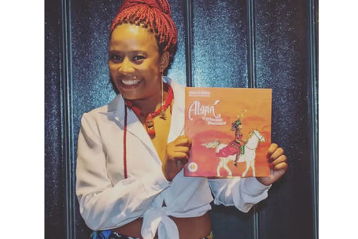 A escritora Sinara Rúbia com o livro de literatura infanto juvenil contando a história de uma princesa negra