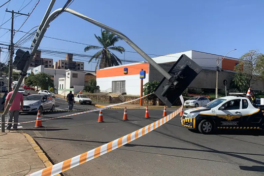 Poste de semáforo no Centro. Caminhões enroscaram nos fios